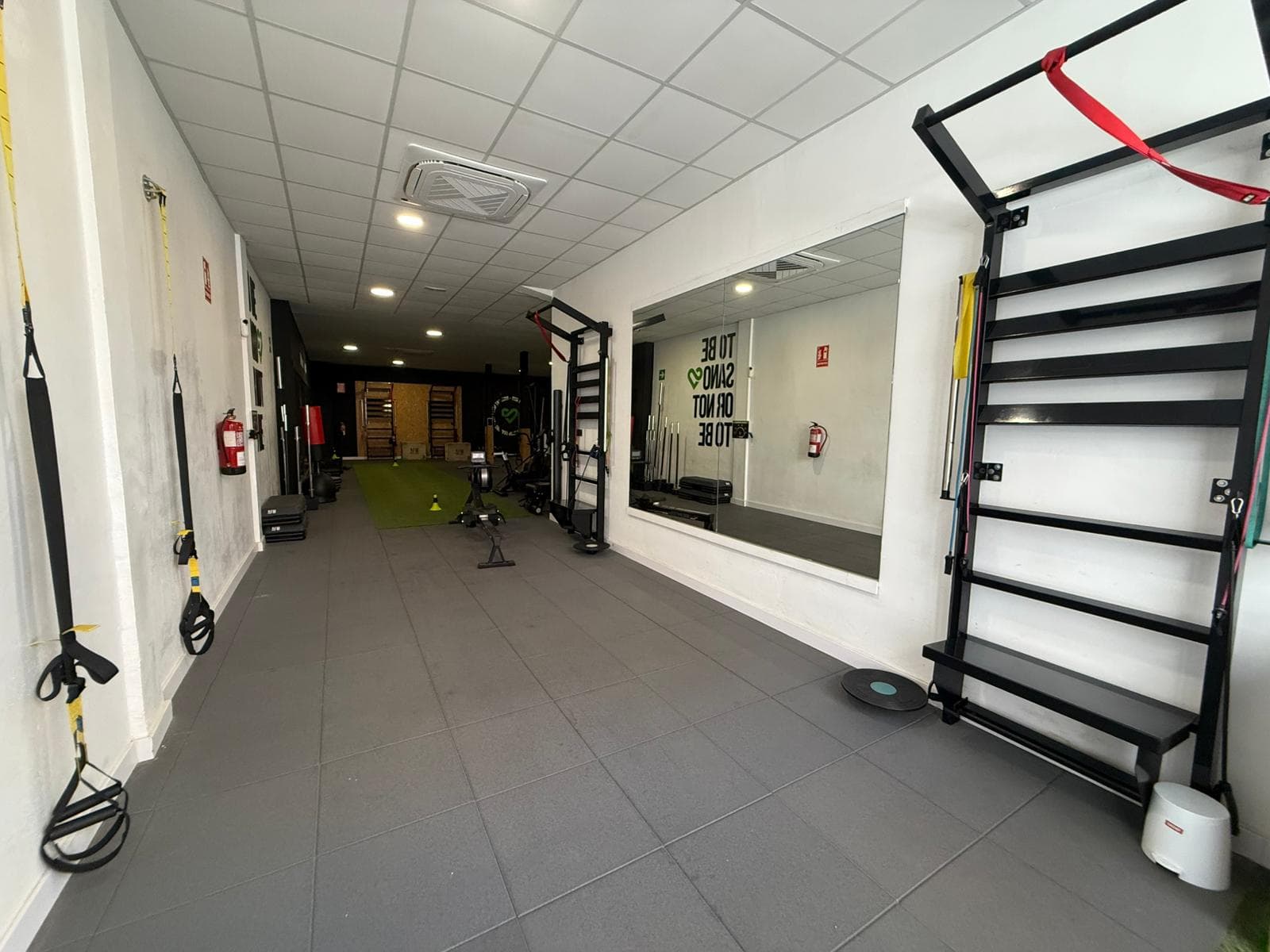Sala principal con remo, TRX y espejo con el lema del centro