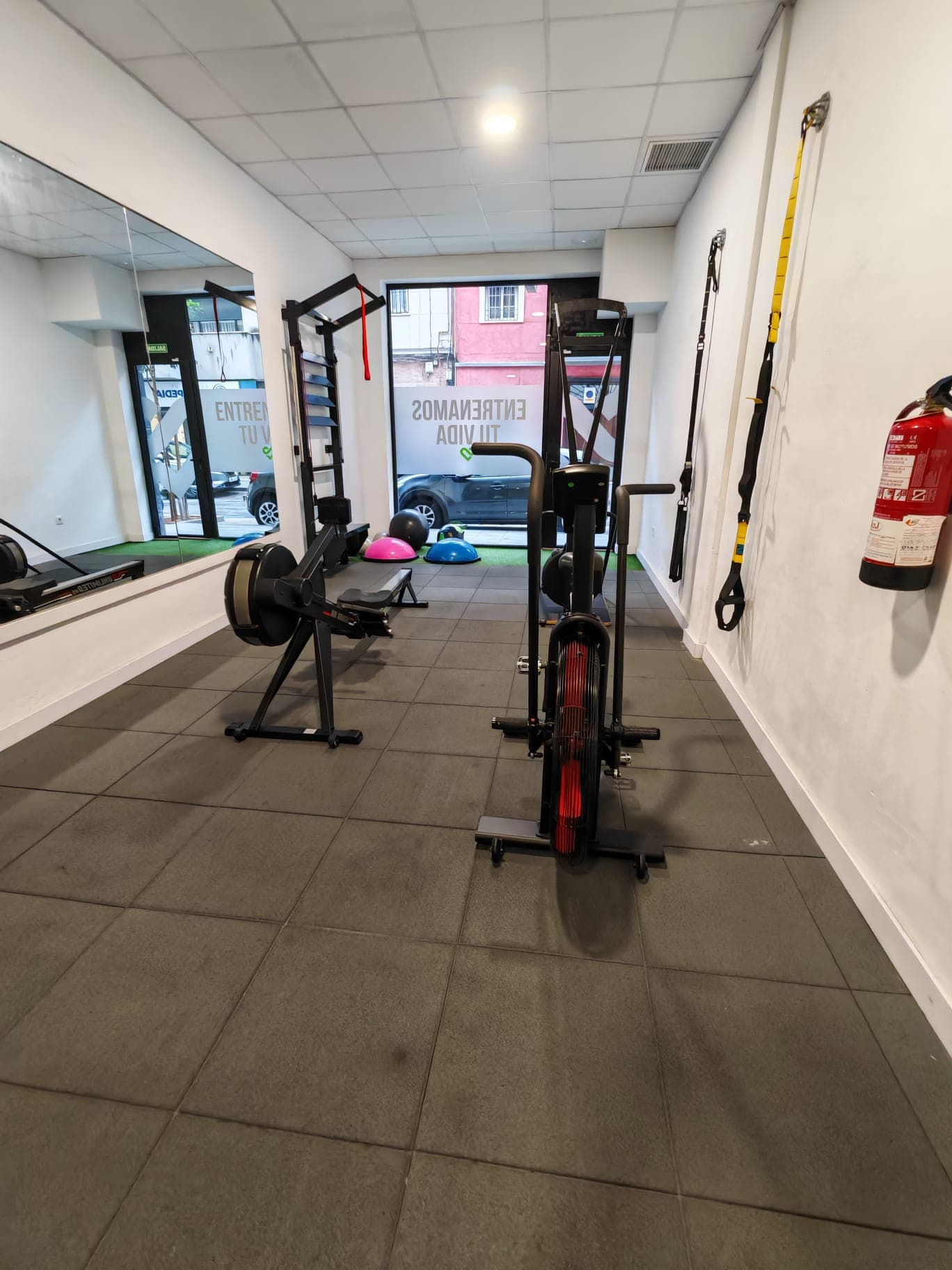 Zona de cardio con remo y bicicleta de aire, junto a la entrada del estudio